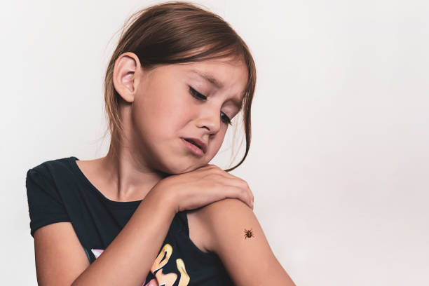A dangerous tick crawls on the child's hand. The girl is afraid of insects.